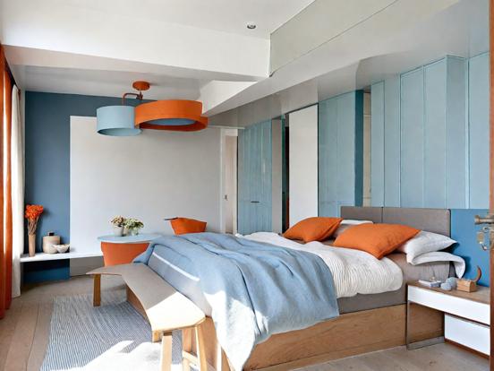 Bed with blue blanket orange pillows