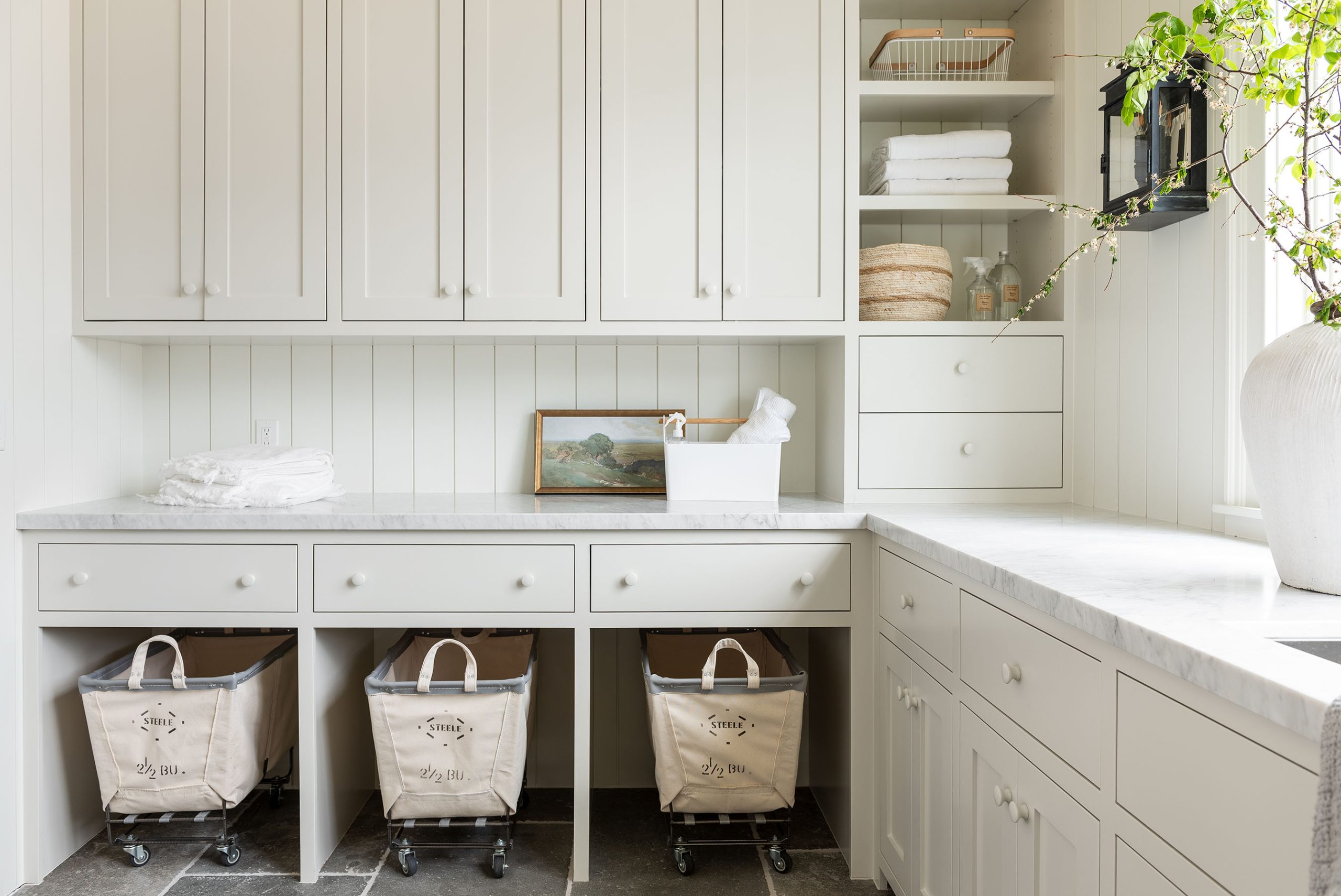 laundry room with white cabinets and white countertops with roller carts